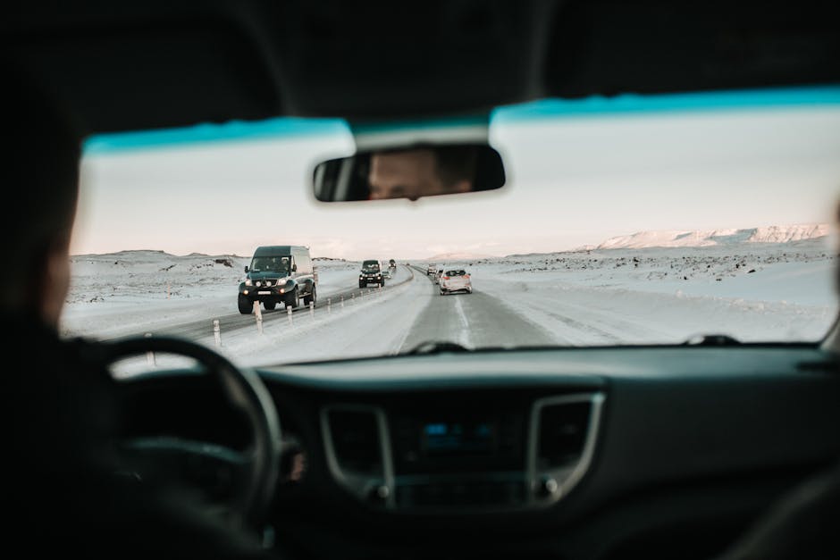 View from inside a car driving on a snowy road through a picturesque winter landscape.